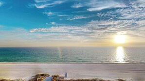A beach with a sunset, a fence, and some vegetation. - Summit 1013 (Panama City Beach)