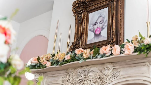 A fireplace with a decorative mantel, a framed picture, and candles. - Pink House (Clarksville)