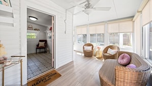 A spacious room with a ceiling fan, wicker furniture, and large windows. - Pink House (Clarksville)
