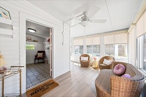 A spacious room with a ceiling fan, wicker furniture, and large windows. - Pink House (Clarksville)