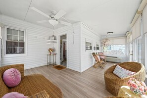 A spacious room with a ceiling fan, wicker furniture, and a dining area with a table and chairs. - Pink House (Clarksville)