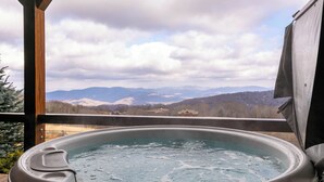 A hot tub with a view of mountains and a cloudy sky.