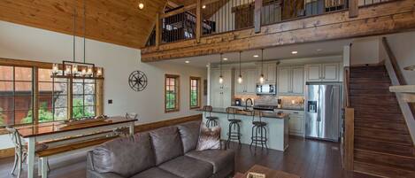A spacious living area with a large gray sofa, a wooden coffee table, and a kitchen in the background.