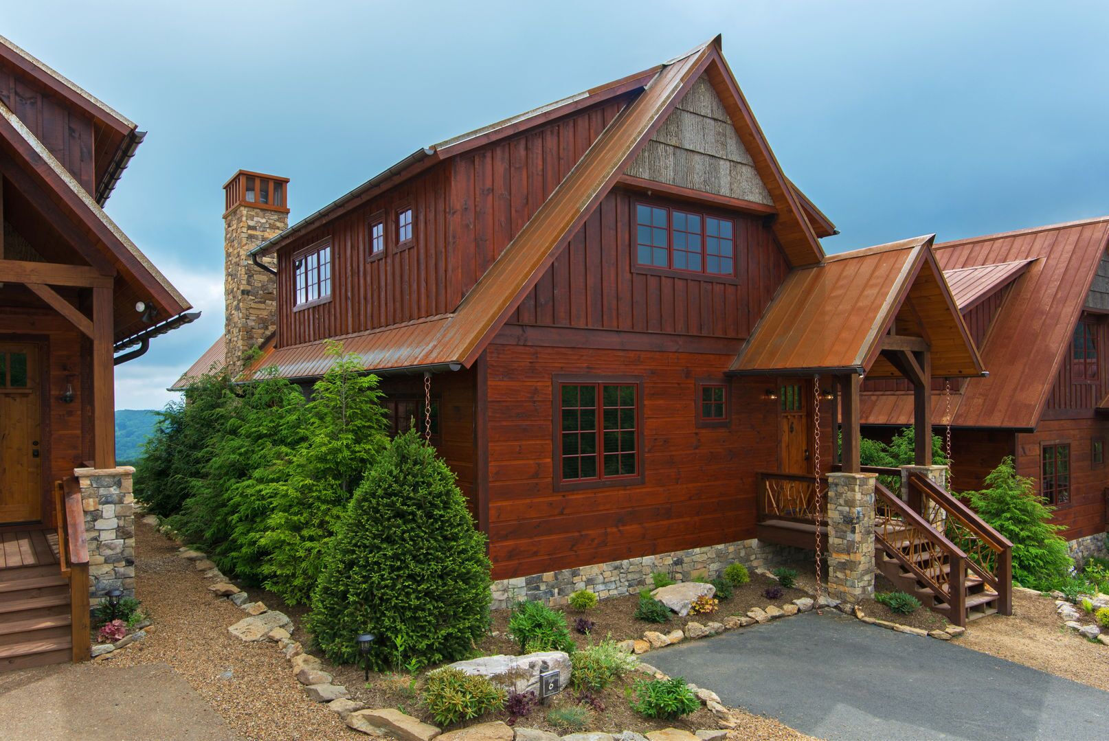 A rustic cabin-style building with a stone chimney, wooden siding, and a stone foundation.