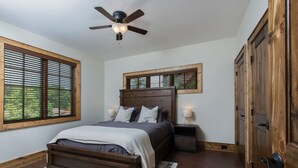 Ein Schlafzimmer mit einem hölzernen Bett, einem Deckenventilator, einem Nachttisch und einem Kleiderschrank.
