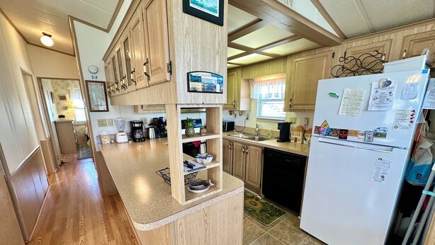 A compact kitchen with wooden cabinets, a white refrigerator, and a small island with a sink. - Cal's Retreat N617 (Jensen Beach)