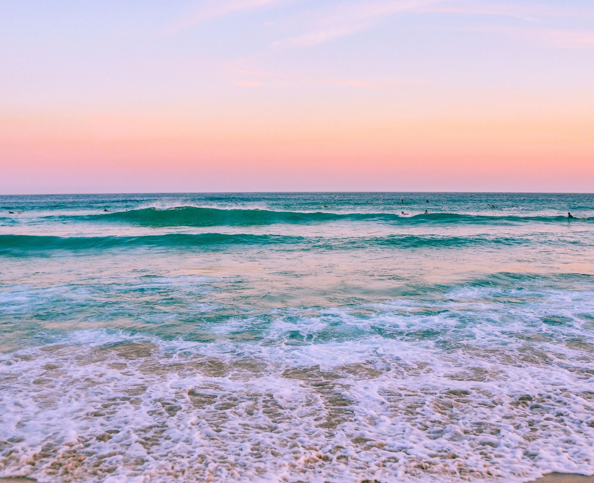 Ein Strand mit Wellen und einem Sonnenuntergangshimmel.