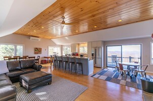 Amplia sala de estar con techo de madera, una cocina con una isla grande y un comedor con vistas.
