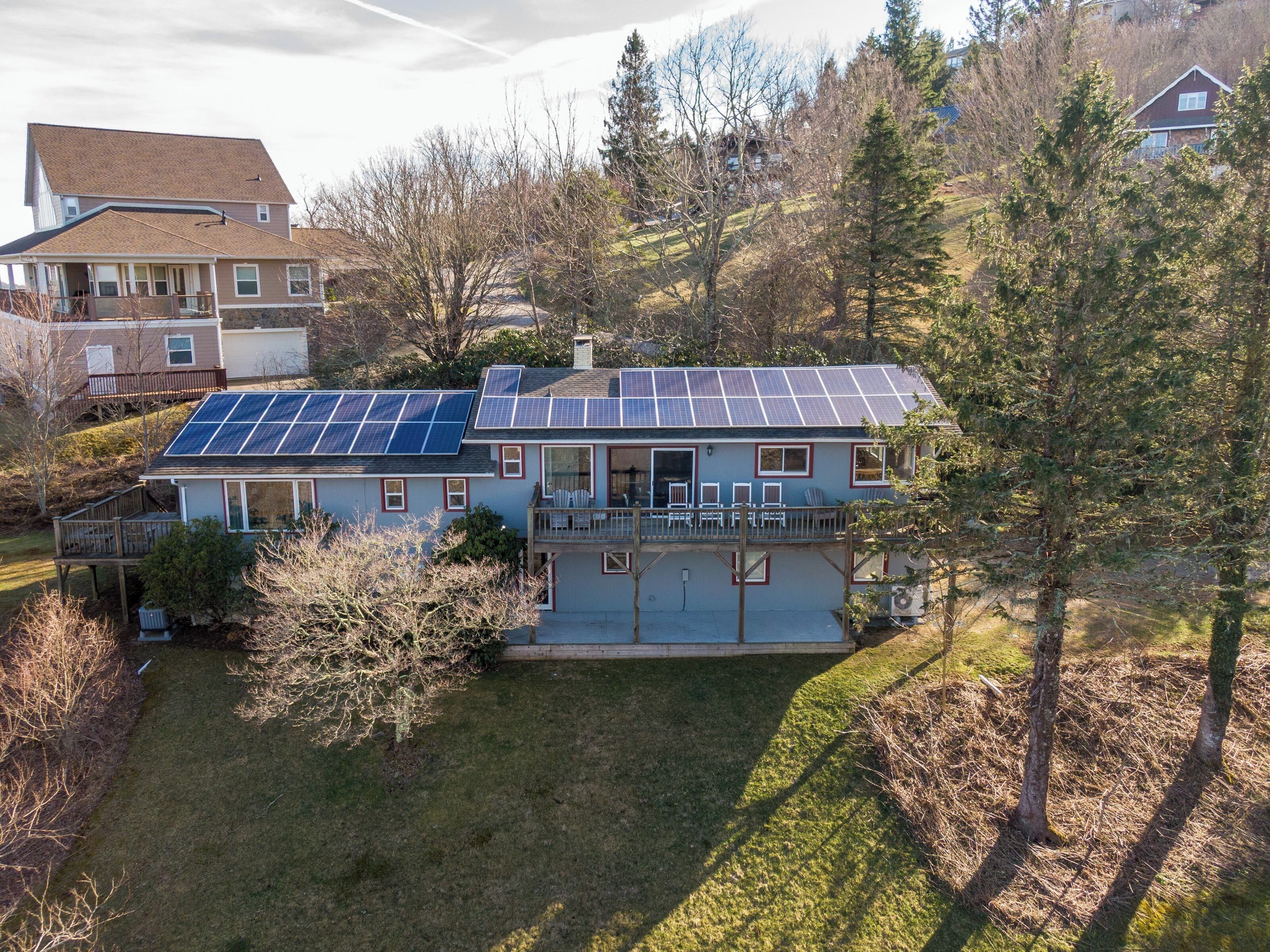 Una casa de dos pisos con un porche cubierto y paneles solares en el techo.