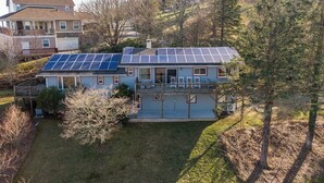 Uma casa de dois andares com varanda coberta e painéis solares no telhado.