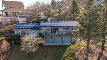 Una casa de dos pisos con un porche cubierto y paneles solares en el techo.
