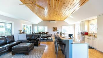 Una cocina moderna con una isla central, techo de madera y ventanas amplias.