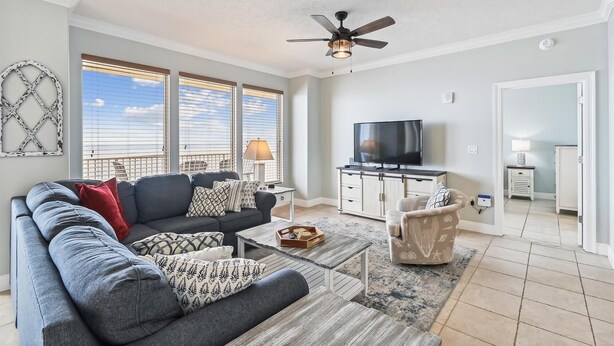 A living room with a sofa, coffee table, TV, and a ceiling fan. - Gulf Crest 2005 (Panama City Beach)
