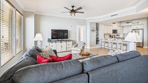 A spacious living room with a grey sofa, a flat-screen TV, and a ceiling fan. - Gulf Crest 2005 (Panama City Beach)