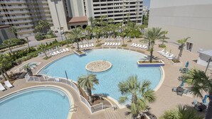 A large outdoor swimming pool with multiple lounge areas and palm trees. - Laketown Wharf 835 (Panama City Beach)