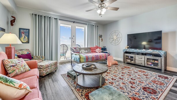 A living room with a sofa, ottoman, coffee table, and a TV stand. - Laketown Wharf 835 (Panama City Beach)