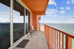 Ein Balkon mit Glastür, zwei Stühlen und Blick aufs Meer.