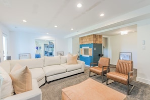 A spacious living area with a large beige sofa, two leather armchairs, and a coffee table.