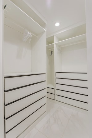 A modern, empty walk-in closet with white shelving and drawers.