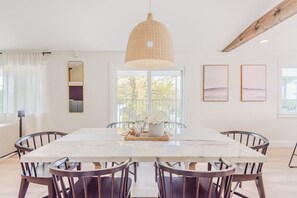 A dining area with a large marble table, dark wooden chairs, a woven pendant light, and framed artwork on the walls. - 72 S Orem Entire Home (Orem)