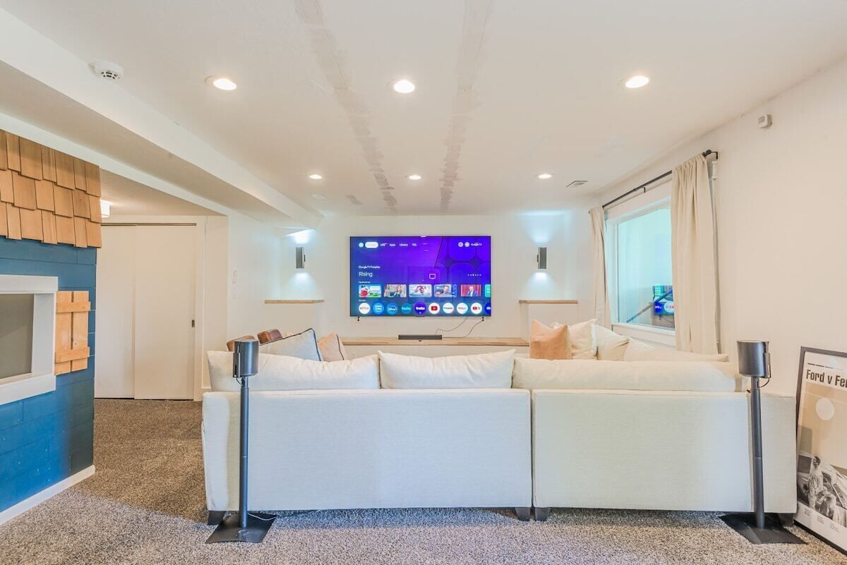 A modern living room with a large flat-screen TV mounted on the wall, a white sofa, and a small coffee table.