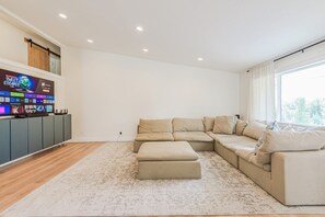 A modern living room with a sectional sofa, a flat-screen TV, and a wooden floor. - 72 S Orem Entire Home (Orem)