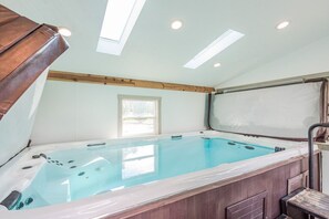 A hot tub with a wooden frame, skylights, and a window.