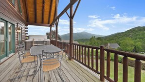 Eine Holzterrasse mit Tisch und Stühlen mit Blick auf eine gebirgige Landschaft.