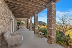 A covered patio with stone pillars, outdoor furniture, and a hot tub. - Mountain Lilly - Huge Views, Three Ensuites, 10min to Blowing Rock (Lenoir)
