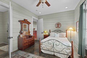 Un dormitorio con cama, cómoda, espejo y ventilador de techo.
