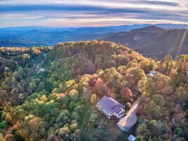 A house surrounded by a forested area with a view of distant mountains.