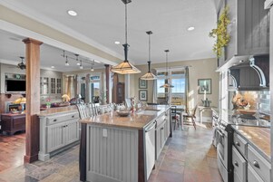 A spacious kitchen with a large island, pendant lighting, and a view to the outside.