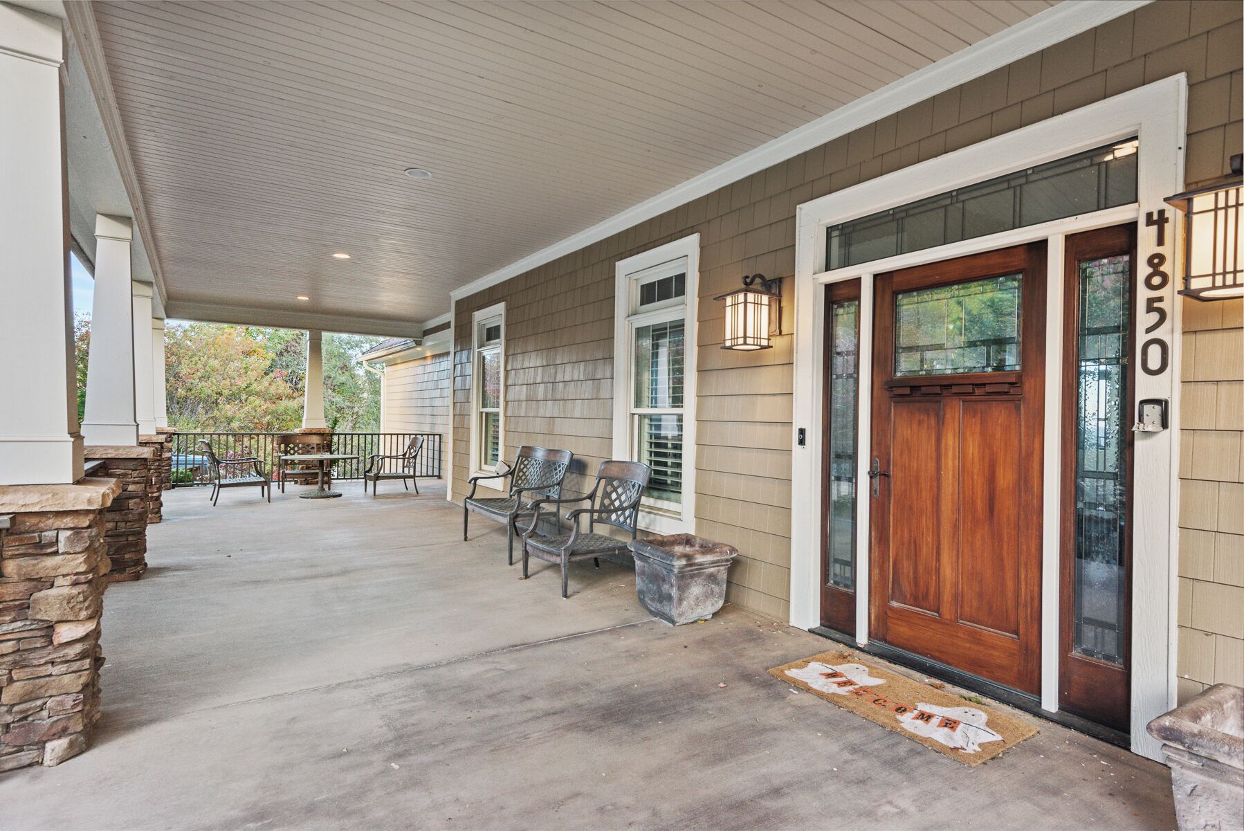 A covered porch with stone accents, a wooden door, and a number '4850' on the wall.