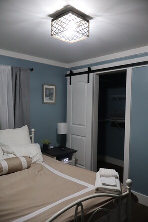 Ein Schlafzimmer mit Bett, Nachttisch, Lampe und Kleiderschrank.