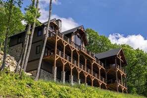 Eine mehrstöckige Blockhütte mit Steinunterbau, Holzbalkonen und großen Fenstern.