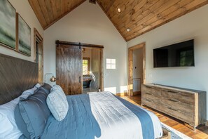 A bedroom with a large bed, wooden ceiling, a TV, and a dresser. - Up and Away at Eagles Nest (Banner Elk)