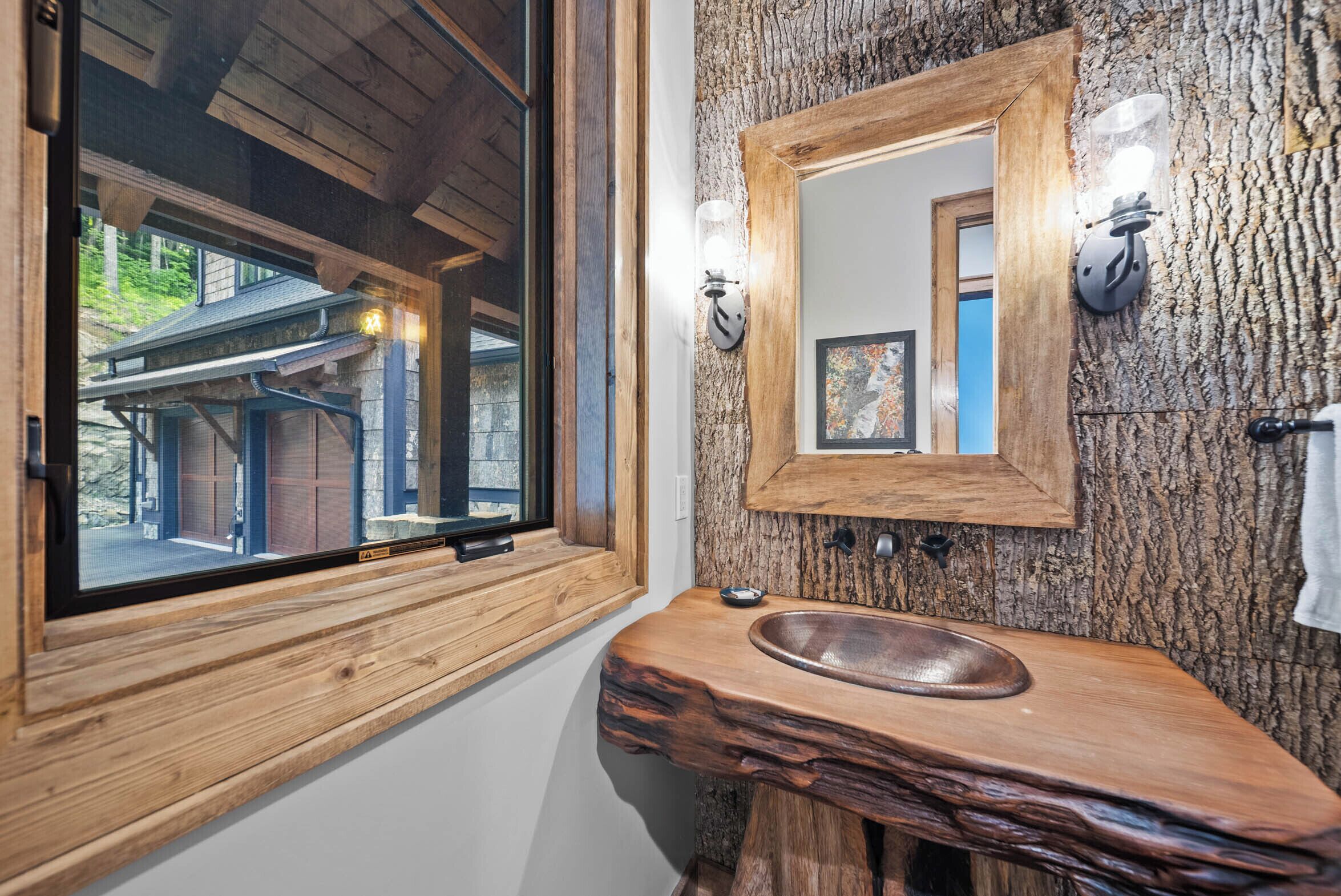 Un baño con tocador de madera, un espejo grande y ventana con vista a un edificio.