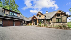 A two-story house with a stone foundation, a large garage, and a well-maintained driveway. - Up and Away at Eagles Nest (Banner Elk)