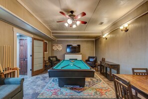 A pool room with a pool table, chairs, a ceiling fan, and a television. - Up Here In the Mountains (Newland)