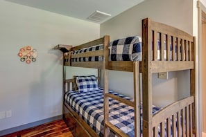 A bunk bed with a checkered bedspread and a pillow, a wooden wall decoration, and a wooden floor. - Adventure Hideaway at Eagles Nest (Banner Elk)