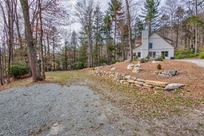 A house with a stone retaining wall, surrounded by a forest. - Adventure Hideaway at Eagles Nest (Banner Elk)