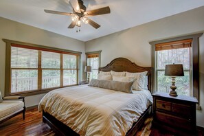 A bedroom with a large bed, a ceiling fan, and a nightstand with a lamp. - Adventure Hideaway at Eagles Nest (Banner Elk)
