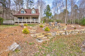 A two-story house with a porch, surrounded by a stone retaining wall and a wooded area. - Adventure Hideaway at Eagles Nest (Banner Elk)