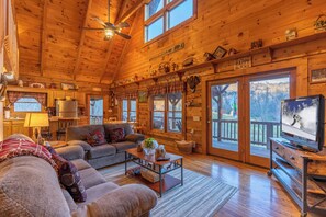 A cozy log cabin interior with a living room, kitchen, and large windows. - Apple Cove (Vilas)