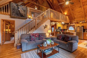 A spacious living area with a large gray sectional sofa, a wooden coffee table, and a staircase leading to an upper level. - Apple Cove (Vilas)