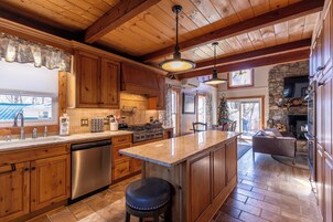 Una cocina amplia con armarios de madera, una isla central, electrodomésticos de acero inoxidable y una chimenea de piedra.