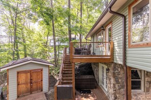 A two-story house with a wooden staircase leading to a balcony, surrounded by trees. - Land Harbor Lodge (Newland)