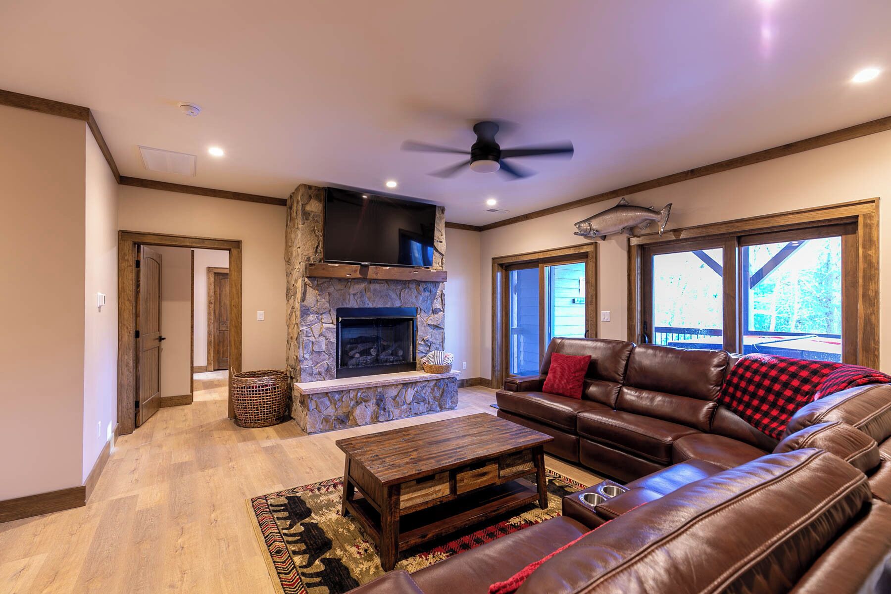 A living room with a stone fireplace, leather sofa, and a television.