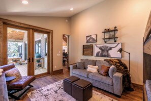 A living room with a sofa, ottoman, and a large window. - Hidden Creek Cabin at Monteagle (Banner Elk)