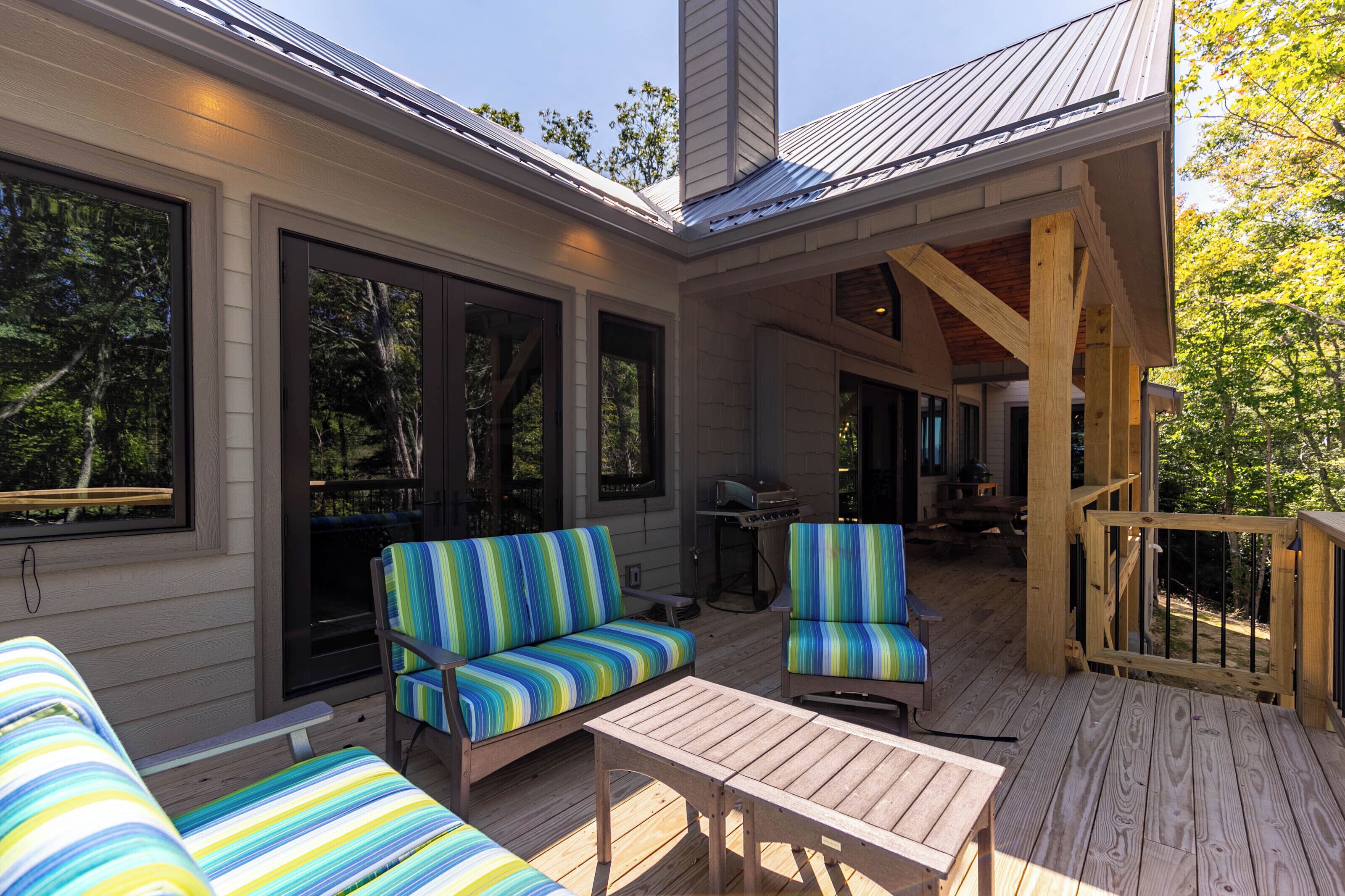 A covered deck with a sofa, chairs, and a table.